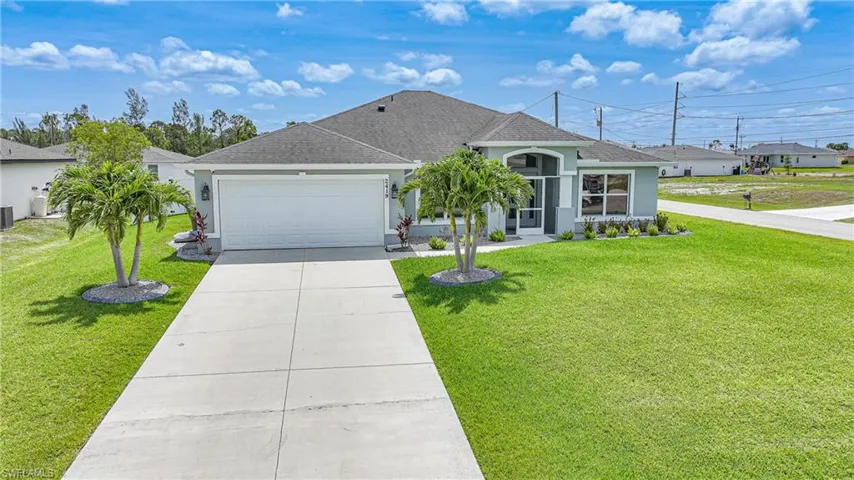 View of front of home with stucco siding, a garage, driveway, and a front yard