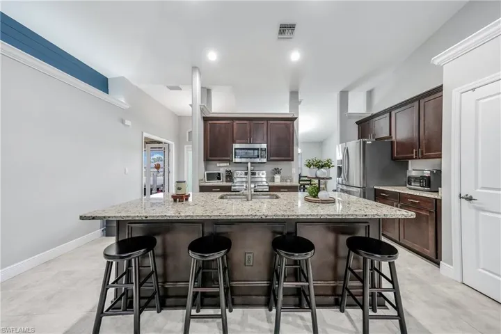 Kitchen with stainless steel appliances, a sink, a kitchen breakfast bar, and a kitchen island with sink