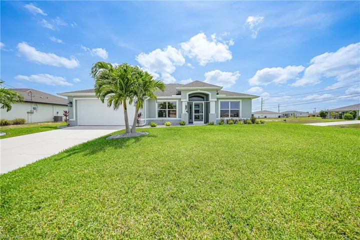 View of front facade with concrete driveway, an attached garage, a front lawn, stucco siding, and roof with shingles