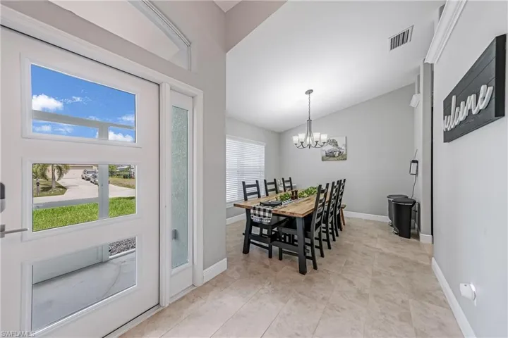 Dining room featuring a chandelier, healthy amount of natural light, vaulted ceiling, and baseboards