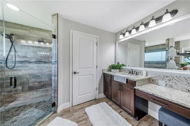 Bathroom with a shower stall, wood finished floors, vanity, and baseboards