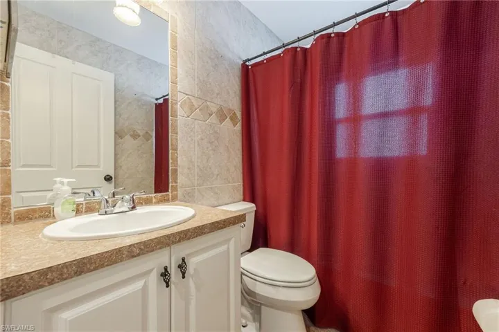Bathroom featuring a single vanity with an oval sink, a light-toned countertop, and white cabinetry with decorative hardware
