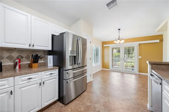 Open-concept kitchen and dining area featuring white cabinetry, stainless steel appliances, and a tiled backsplash