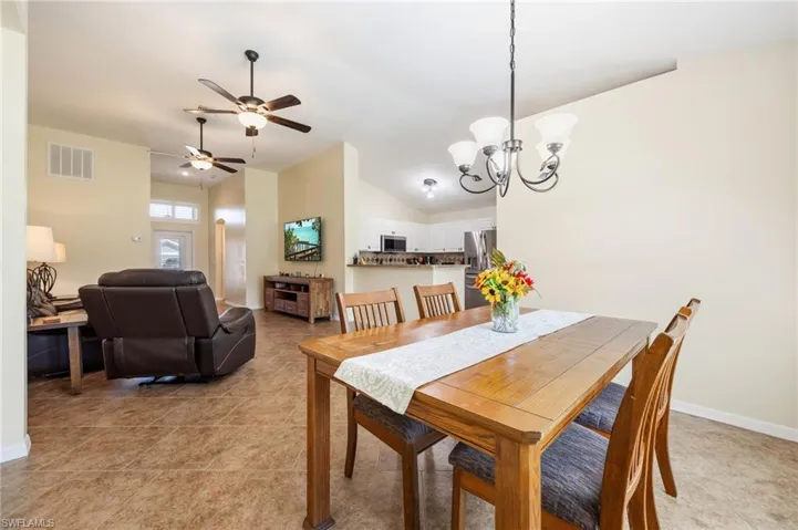Open-concept living and dining areas featuring tile flooring, vaulted ceilings, and ceiling fans with integrated lighting
