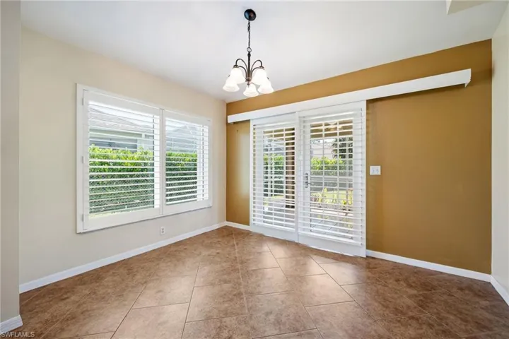Eat in kitchen featuring custom sliding plantation shutters featuring tile flooring and a multi-light chandelier
