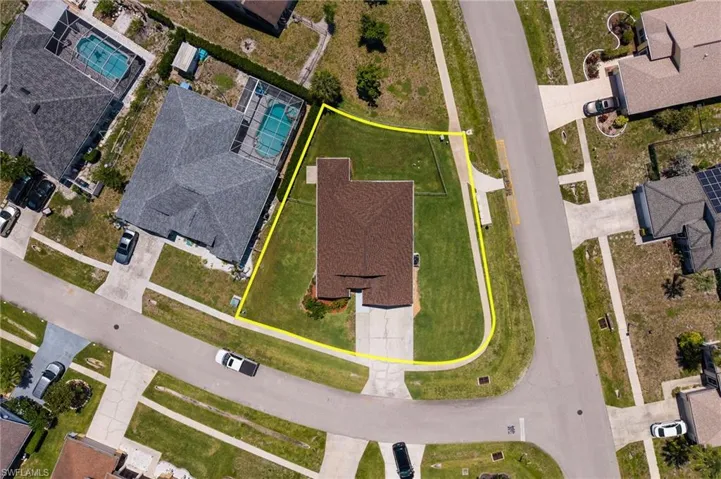Corner lot property featuring a brown shingle roof, green lawn, and concrete driveway