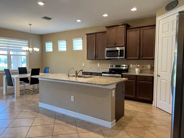 Kitchen featuring dark brown cabinetry, light tile patterned floors, recessed lighting, stainless steel appliances, and pendant lighting