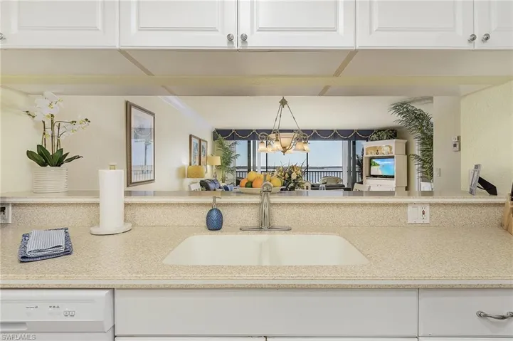 Kitchen featuring dishwasher, sink, a notable chandelier, decorative light fixtures, and white cabinetry
