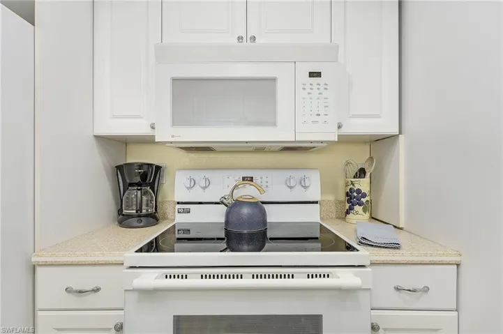 Kitchen featuring white cabinets and white appliances