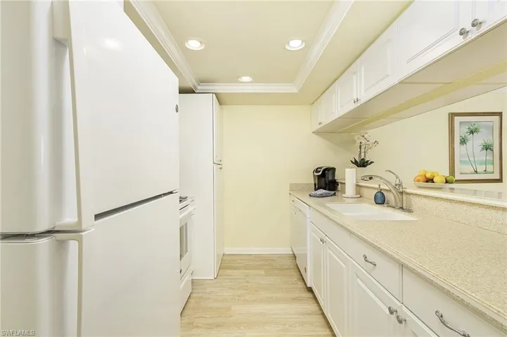 Kitchen featuring crown molding, sink, light wood-type flooring, white cabinets, and white appliances