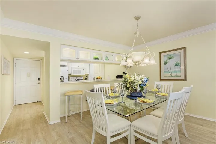Dining space with light hardwood / wood-style floors, crown molding, and a chandelier