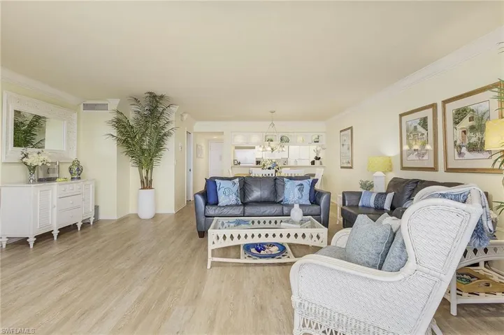 Living room featuring light hardwood / wood-style floors, crown molding, and an inviting chandelier