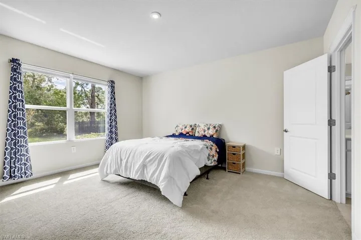 Light-colored carpeted flooring, neutral wall tones, and a large window