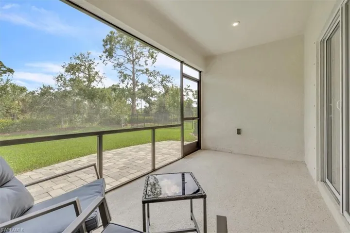 Screened lanai featuring a textured concrete floor and recessed lighting