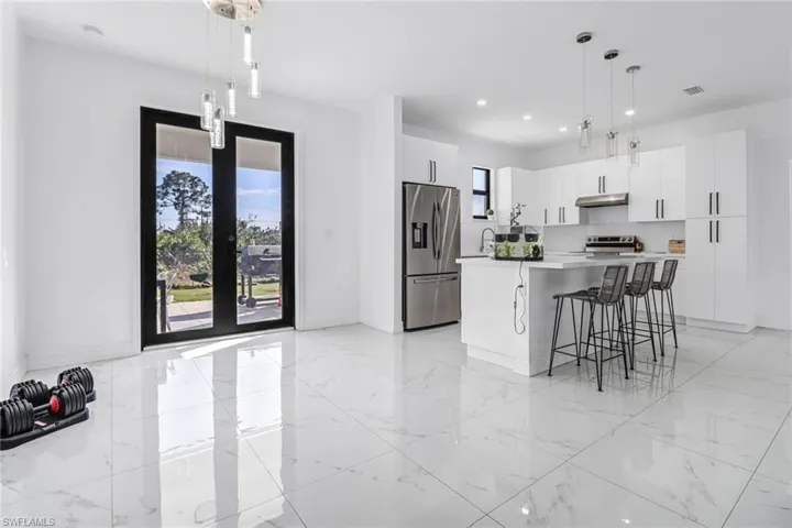 Kitchen featuring white cabinetry, hanging light fixtures, light tile patterned floors, a center island, and stainless steel appliances