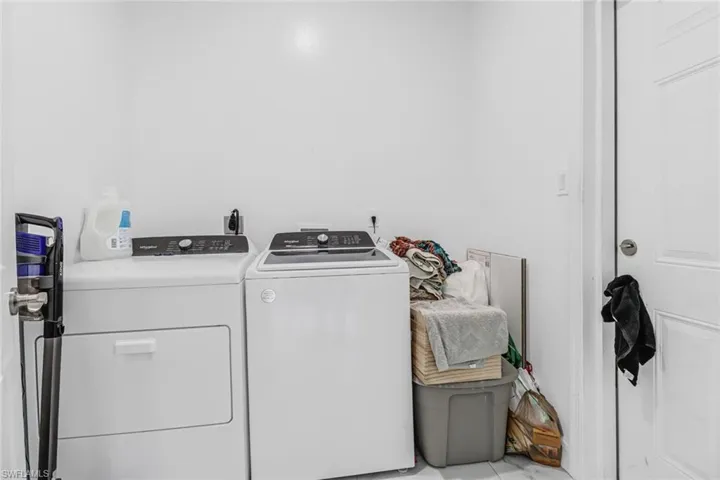 Clothes washing area featuring washing machine and clothes dryer and light tile patterned flooring