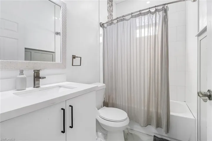 Full bathroom with toilet, vanity, and shower / bath combination with curtain
