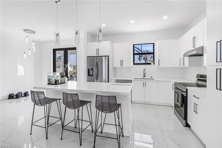 Kitchen featuring pendant lighting, appliances with stainless steel finishes, light tile patterned flooring, sink, and white cabinetry