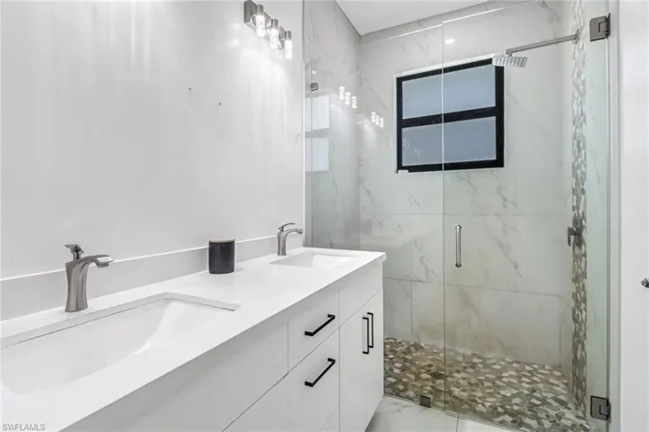 Bathroom featuring tile patterned floors, a shower with door, and dual vanity