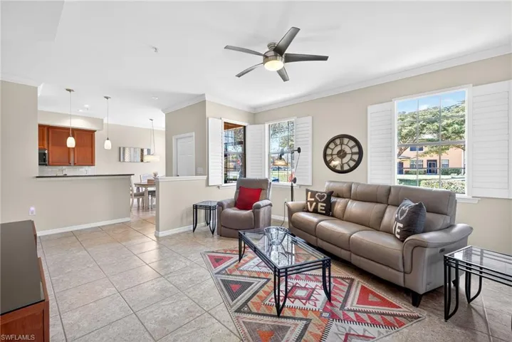 Living room with ornamental molding, a ceiling fan, and light tile patterned floors