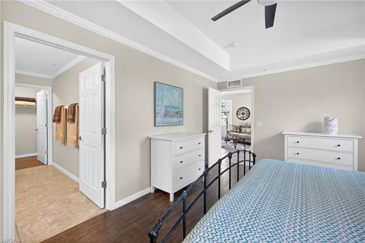 Bedroom with wood finished floors, ornamental molding, a ceiling fan, and a walk in closet
