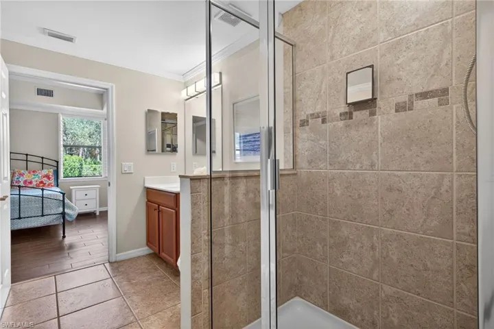 Ensuite bathroom featuring vanity, ornamental molding, and a shower stall