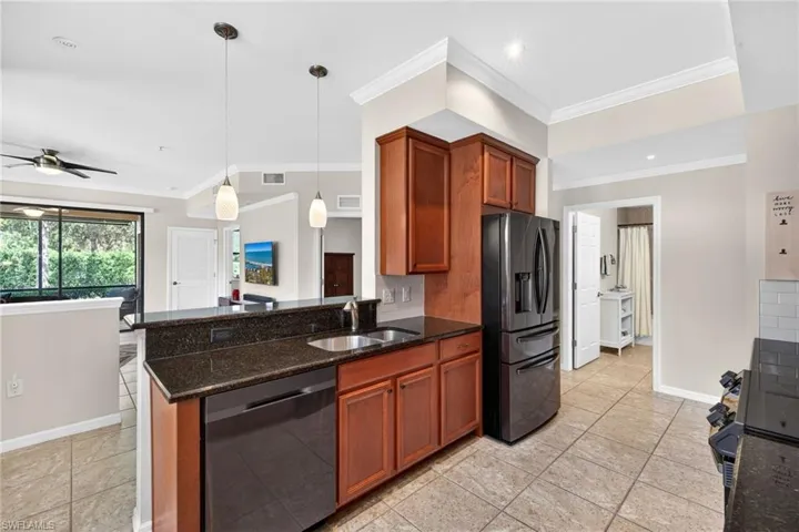 Kitchen featuring dark stone counters, dishwashing machine, black fridge with ice dispenser, pendant lighting, and wood finish cabinetry