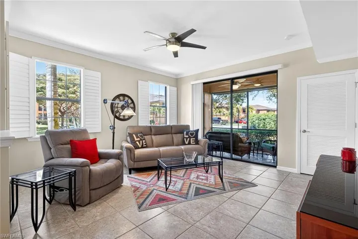 Living area with ceiling fan, light tile patterned floors, and crown molding