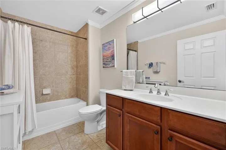 Full bath with vanity, shower / bath combo, ornamental molding, and light tile patterned floors