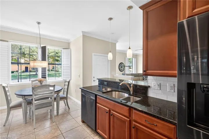 Kitchen with refrigerator with ice dispenser, dark stone countertops, wood finish cabinetry, a peninsula, and crown molding