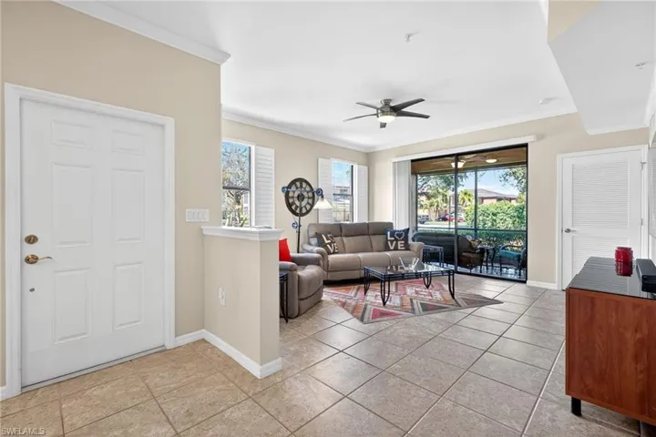 Living room with a ceiling fan, crown molding, healthy amount of natural light, and light tile patterned floors