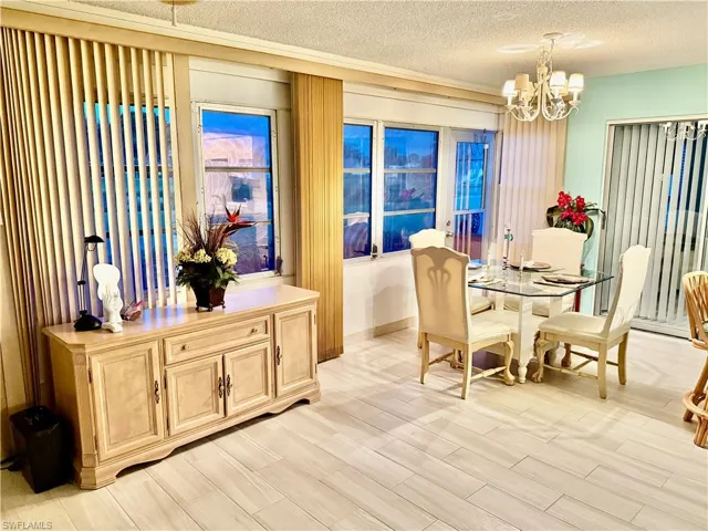 Dining room with a textured ceiling, light wood-style flooring, and a chandelier