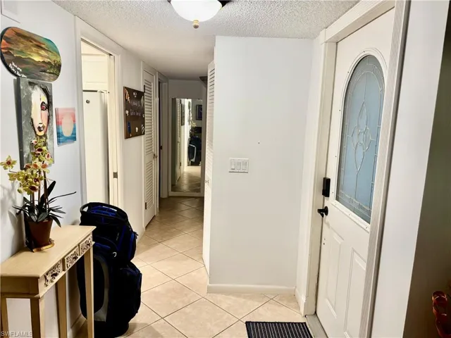 Hallway featuring a textured ceiling and light tile patterned flooring