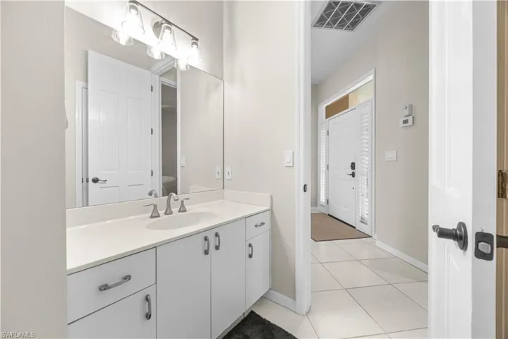 This bathroom features a spacious vanity with white cabinetry, a light-colored countertop, and a large mirror