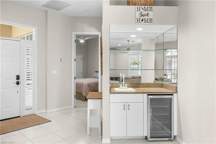 Entryway featuring white tiled flooring and a white front door with louvered side panels