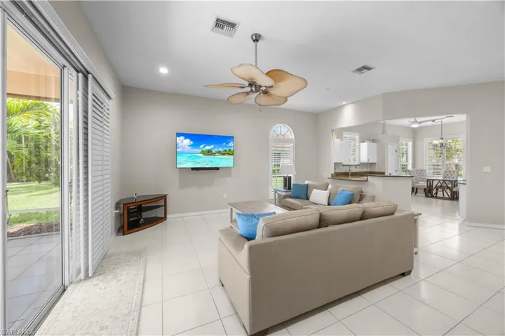 Bright living area featuring tiled flooring, a ceiling fan, and sliding glass doors leading to the outdoor space