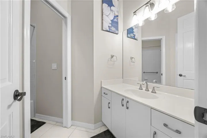 Bathroom featuring a vanity with a white countertop and sink, brushed nickel faucet, and an illuminated mirror