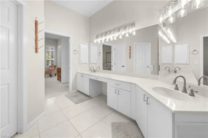 This bathroom features a double vanity with white cabinetry and light-colored countertops