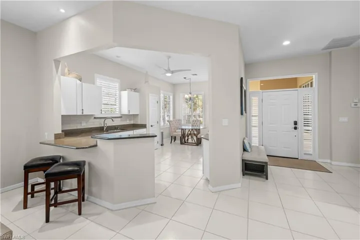 The property features an open-concept living area with tile flooring, a kitchen with white cabinetry and a breakfast bar, and a dining area with a chandelier