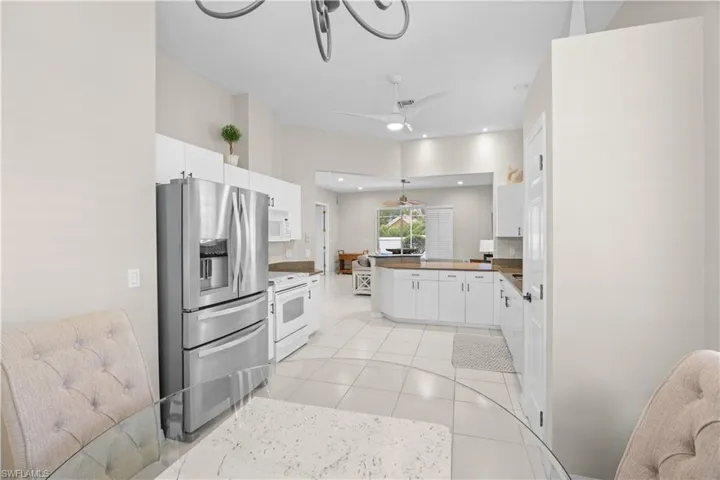 The kitchen features stainless steel appliances, white cabinetry, a tiled floor, and recessed lighting
