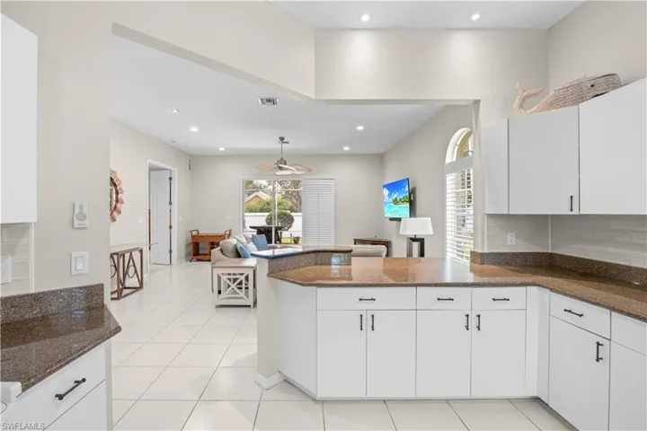 The kitchen features white cabinetry, granite countertops, and a tile backsplash, with tile flooring extending throughout the space