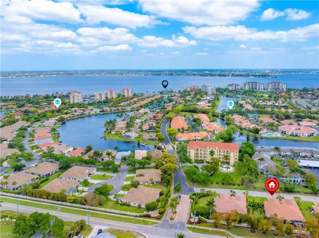 Aerial view of the property's community, featuring a large body of water, residential properties with landscaping, and a distant coastline