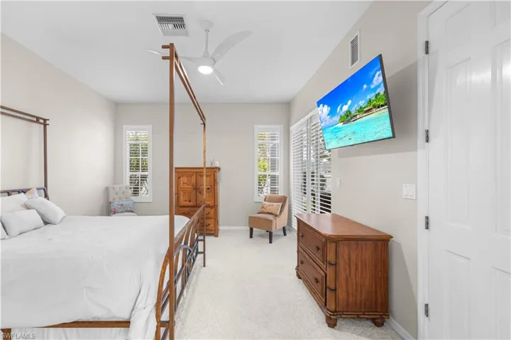 This room features light-colored walls, carpeted flooring, and a ceiling fan