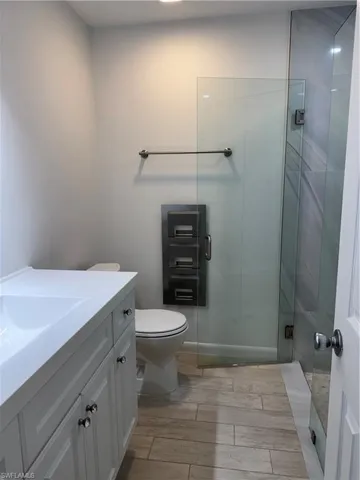 Full bathroom with toilet, a shower stall, wood finish floors, and vanity