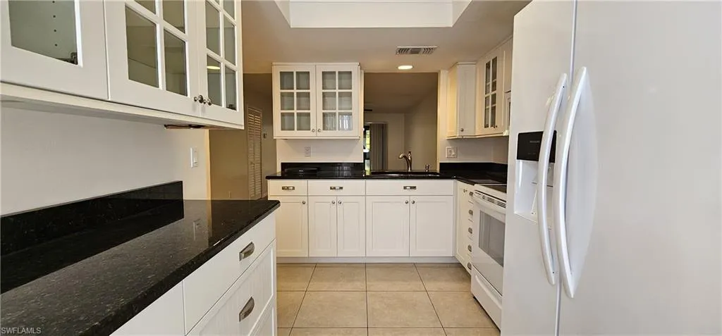Kitchen featuring white appliances, white cabinets, light tile patterned floors, and recessed lighting