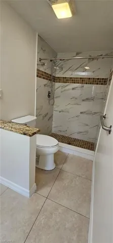 Bathroom with a shower stall, light tile patterned floors, and vanity