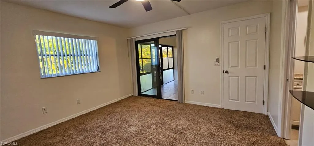 Empty room featuring dark carpet and ceiling fan