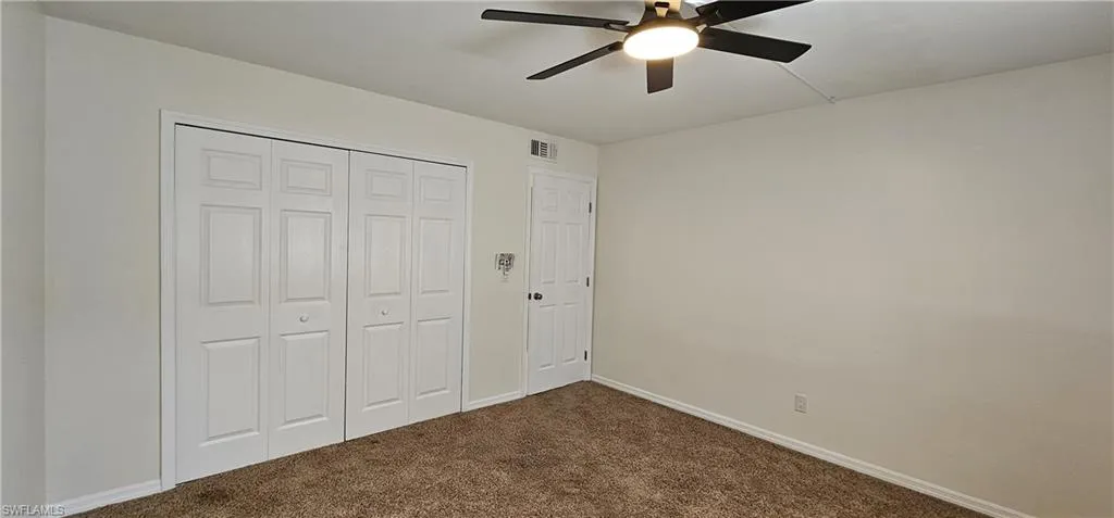 Guest bedroom featuring dark carpet, a closet, and ceiling fan