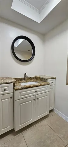 Bathroom with vanity, light tile patterned floors, and crown molding