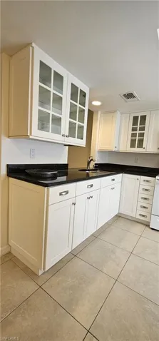 Kitchen with glass insert cabinets, white cabinets, light tile patterned floors, and white range oven